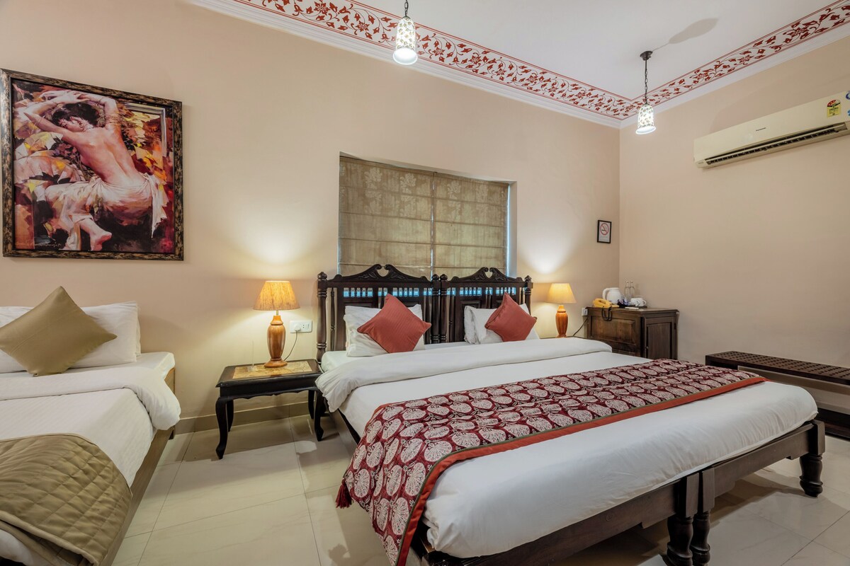 A hotel room with two beds, a large painting, a window, and an air conditioning unit.