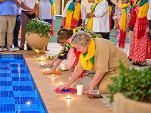 Um grupo de pessoas realizando um ritual à beira da piscina, com velas e oferendas.