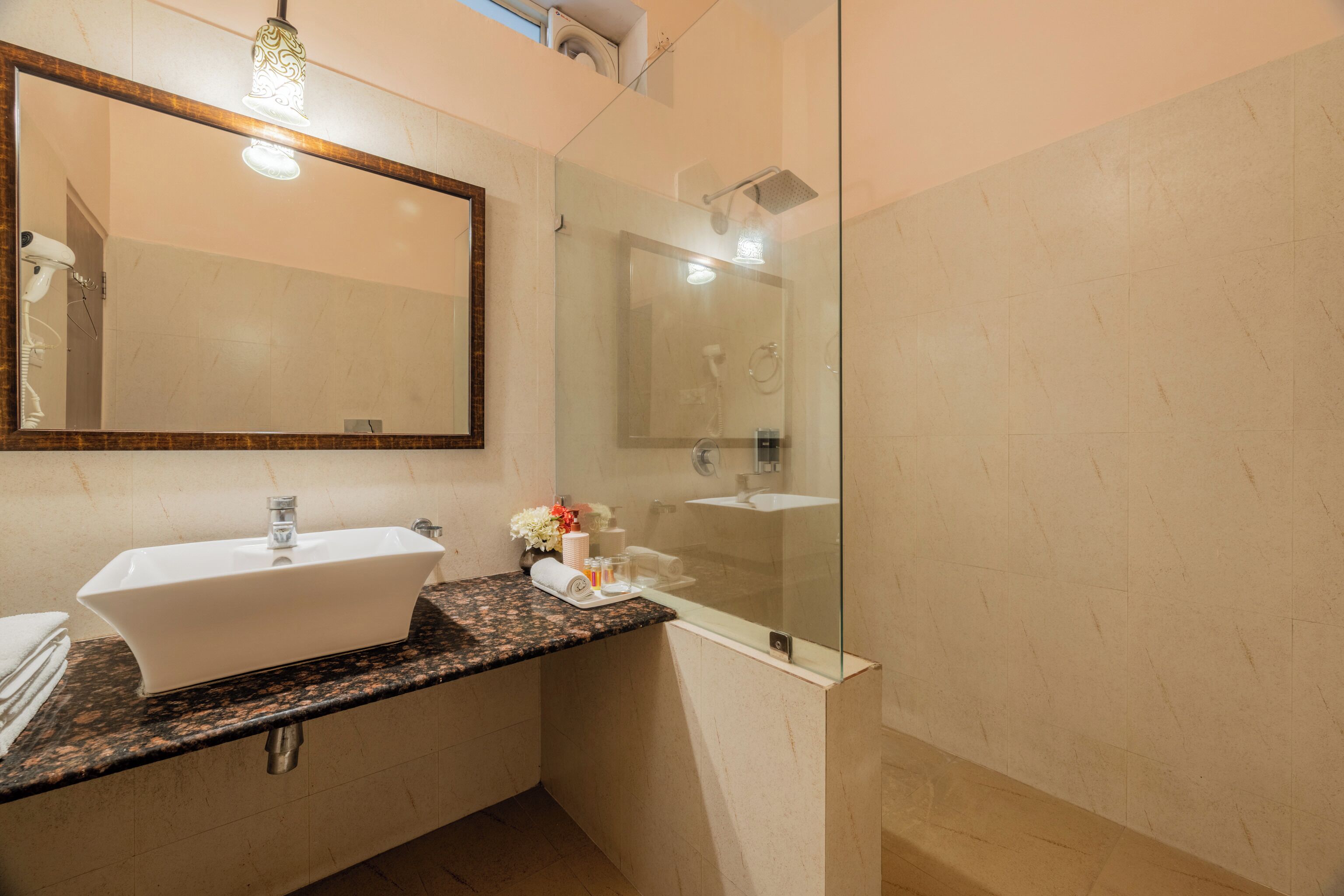 A bathroom with a white sink, a glass shower enclosure, and a large mirror.
