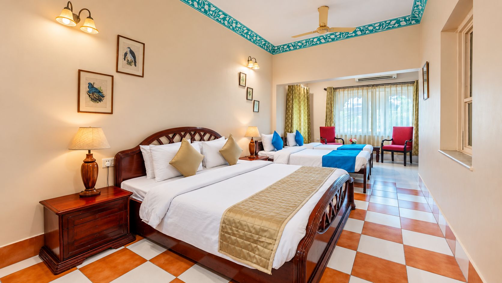A hotel room with two beds, a wooden headboard, a nightstand, a lamp, a chair, and a window with curtains.