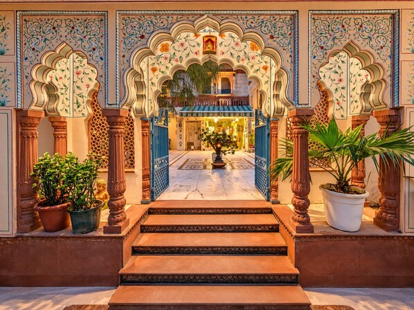 Una entrada imponente con arcos decorativos y una escalera central que conduce a un interior luminoso.