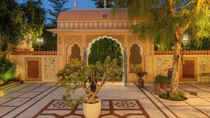 A courtyard with a potted tree, tiled floor, and ornate architectural details. - Suryaa Villa - A City Centre Hotel (Jaipur)