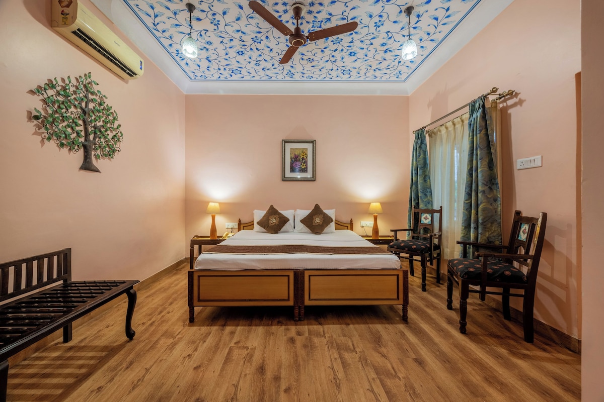 Ein Schlafzimmer mit einem hölzernen Bett, zwei Nachttischen, einer Bank, einem Deckenventilator und einer Wand-Klimaanlage.
