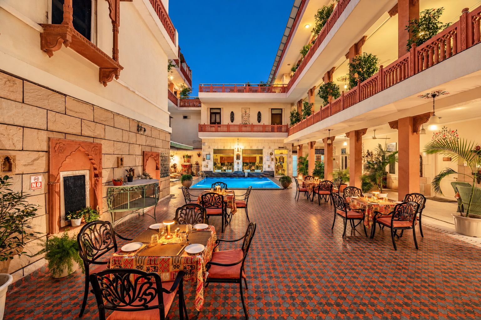A courtyard with a pool, dining area, and multiple balconies with plants.