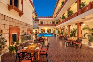 Un patio con piscina, zona de comedor y varios balcones con plantas.