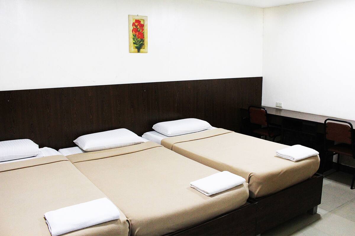 Ein Hotelzimmer mit zwei Einzelbetten, einem Schreibtisch und einem Stuhl.