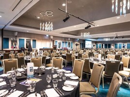 Une salle de conférence équipée de tables rondes, de chaises et d’un écran de projection.