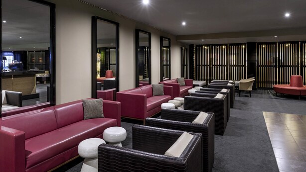 Un área de lounge moderna con sofás de cuero, otomanas blancas y negras, y un mostrador de recepción.