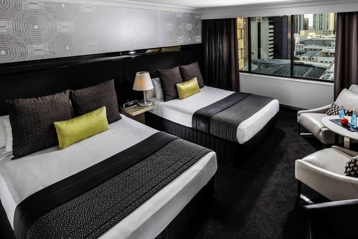 A hotel room with two beds, a desk, and a chair.
