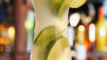 A cocktail glass with lime slices and a lime garnish on a bar counter.