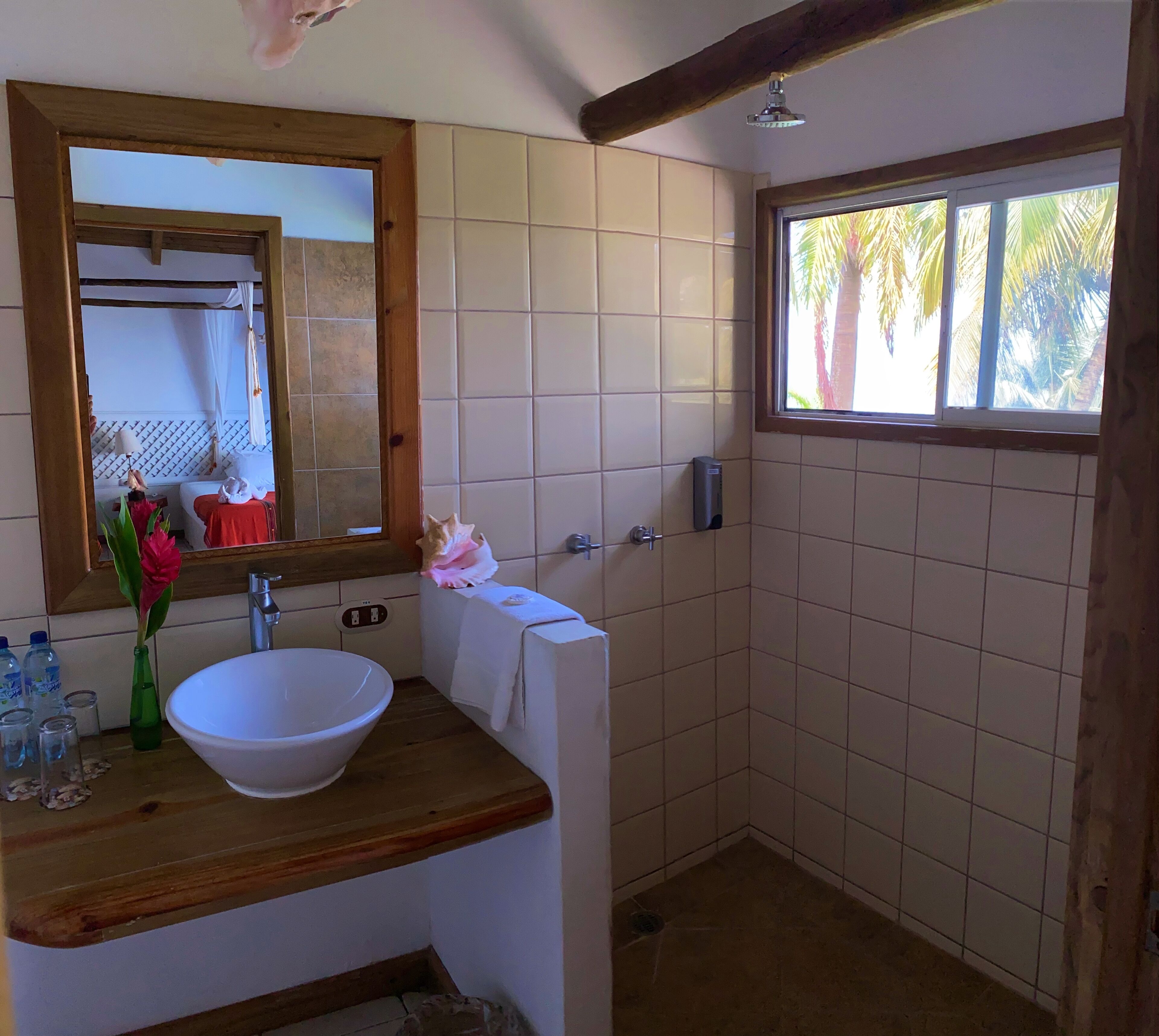Un baño con un espejo grande, un lavamanos blanco y una zona de ducha.