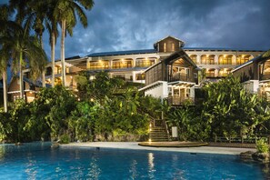 A resort with a swimming pool, palm trees, and a large building with multiple balconies.