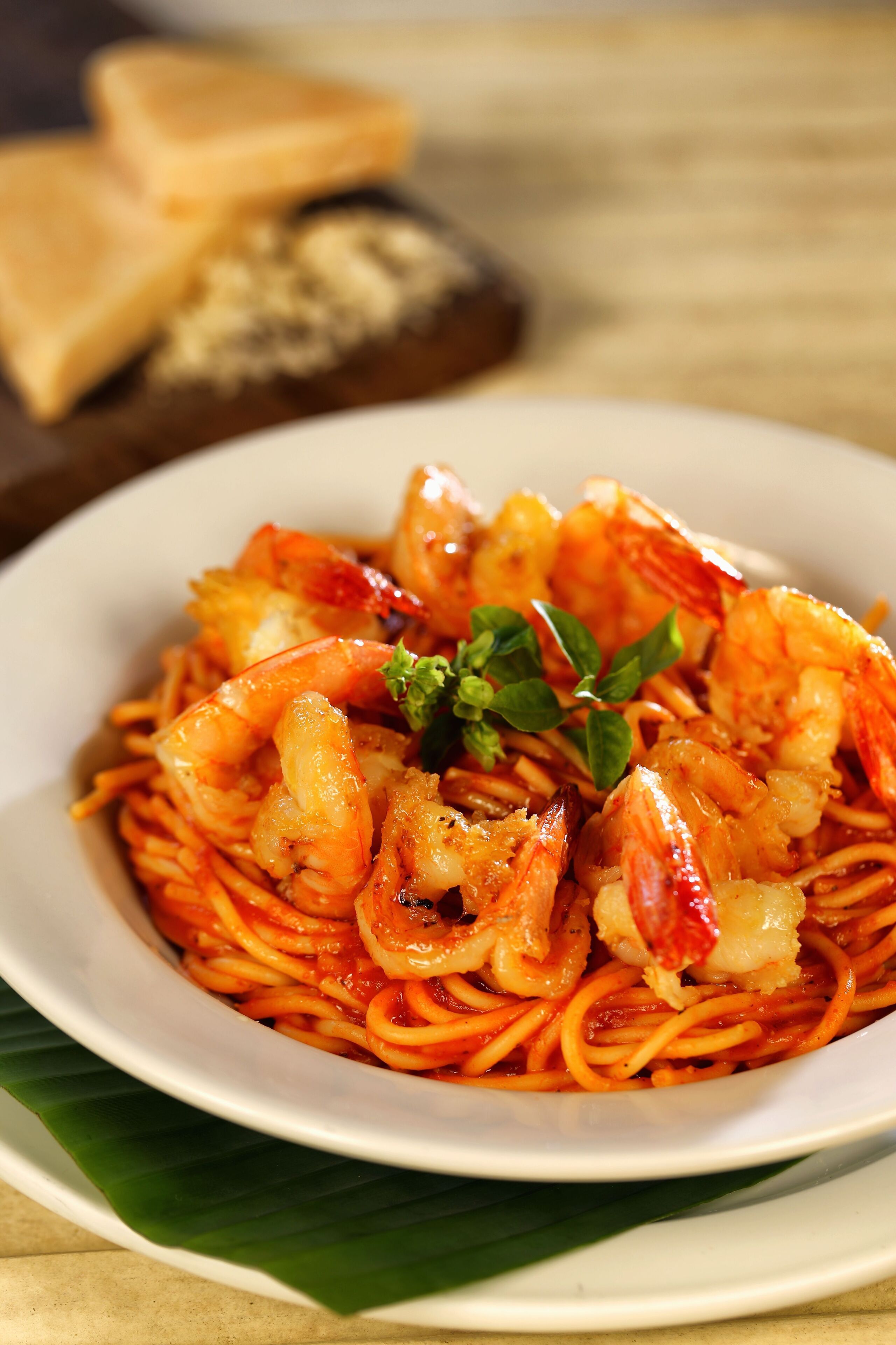 A plate of spaghetti with shrimp and basil.