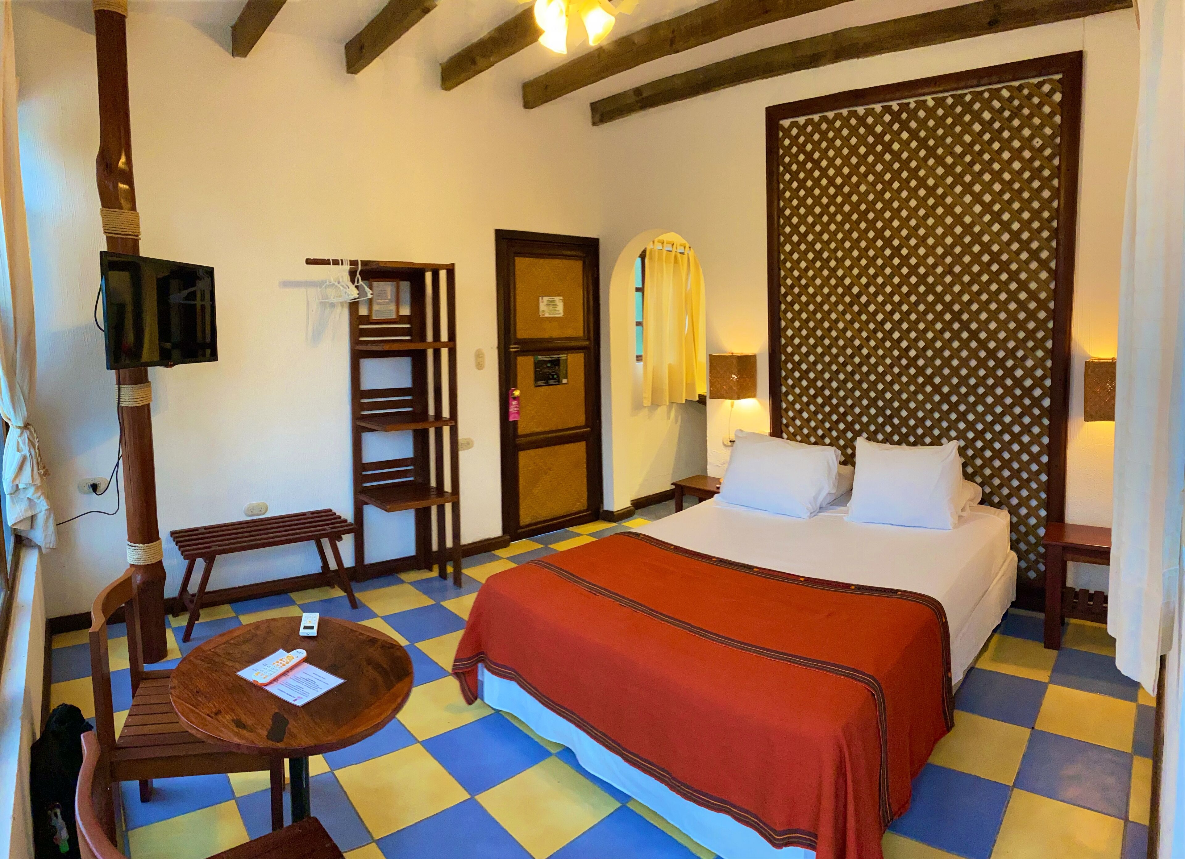Una habitación de hotel con cama, escritorio, silla, televisor y pared con diseño.