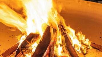 A fire burning in a metal fire pit with logs and bricks.