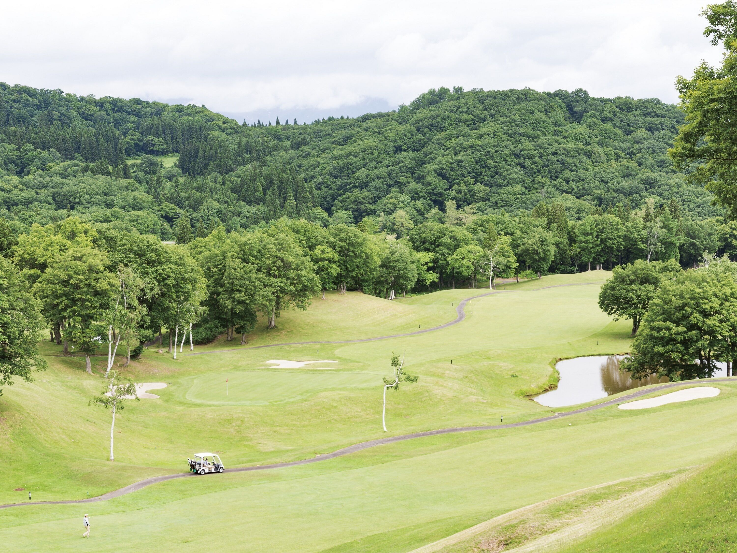 Un campo de golf con un fairway verde, búnkeres de arena y un obstáculo acuático.