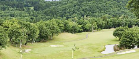 Un campo de golf con un fairway verde, búnkeres de arena y un obstáculo acuático.