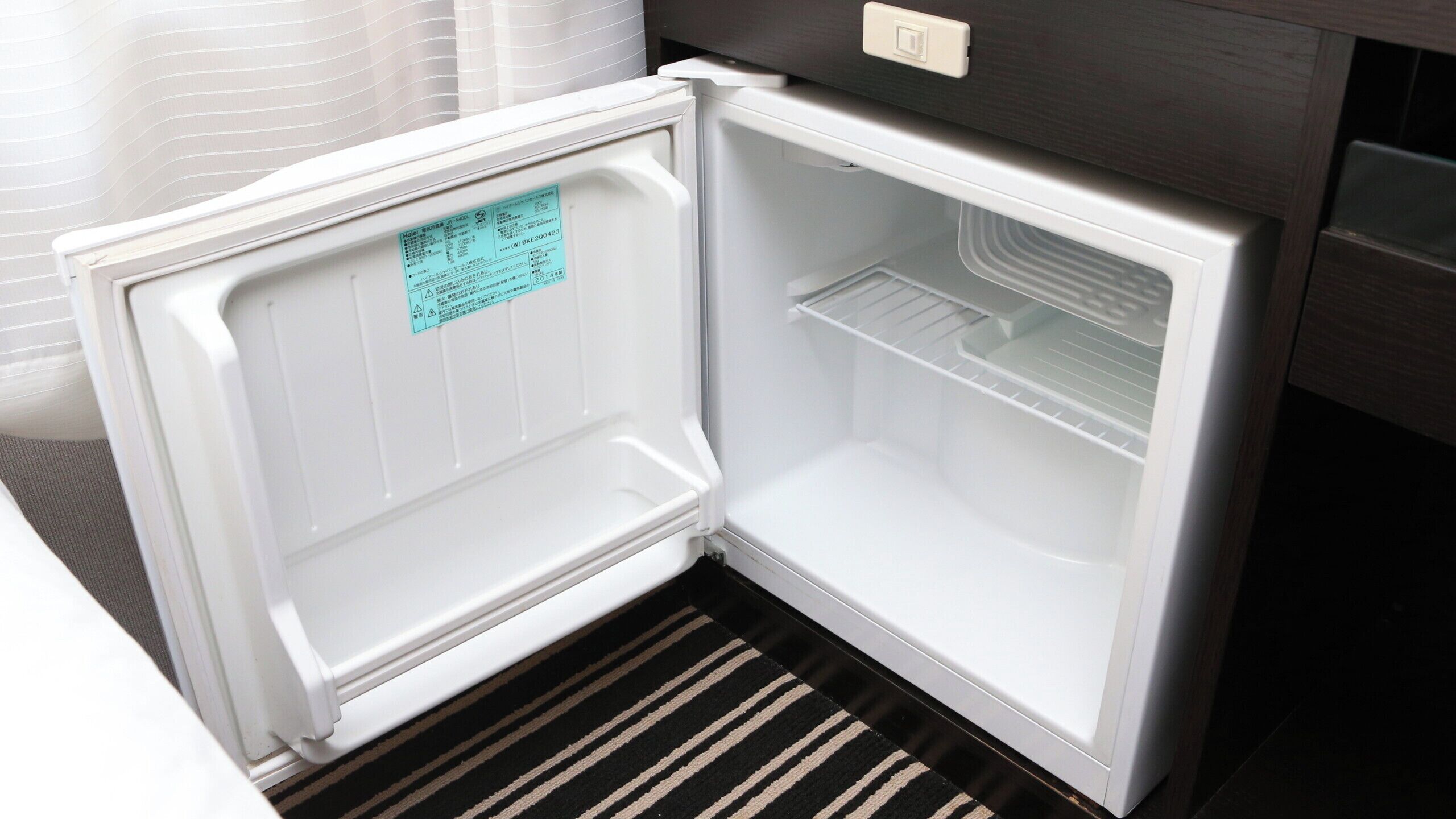 An open refrigerator with a control panel and a warning label on the door.