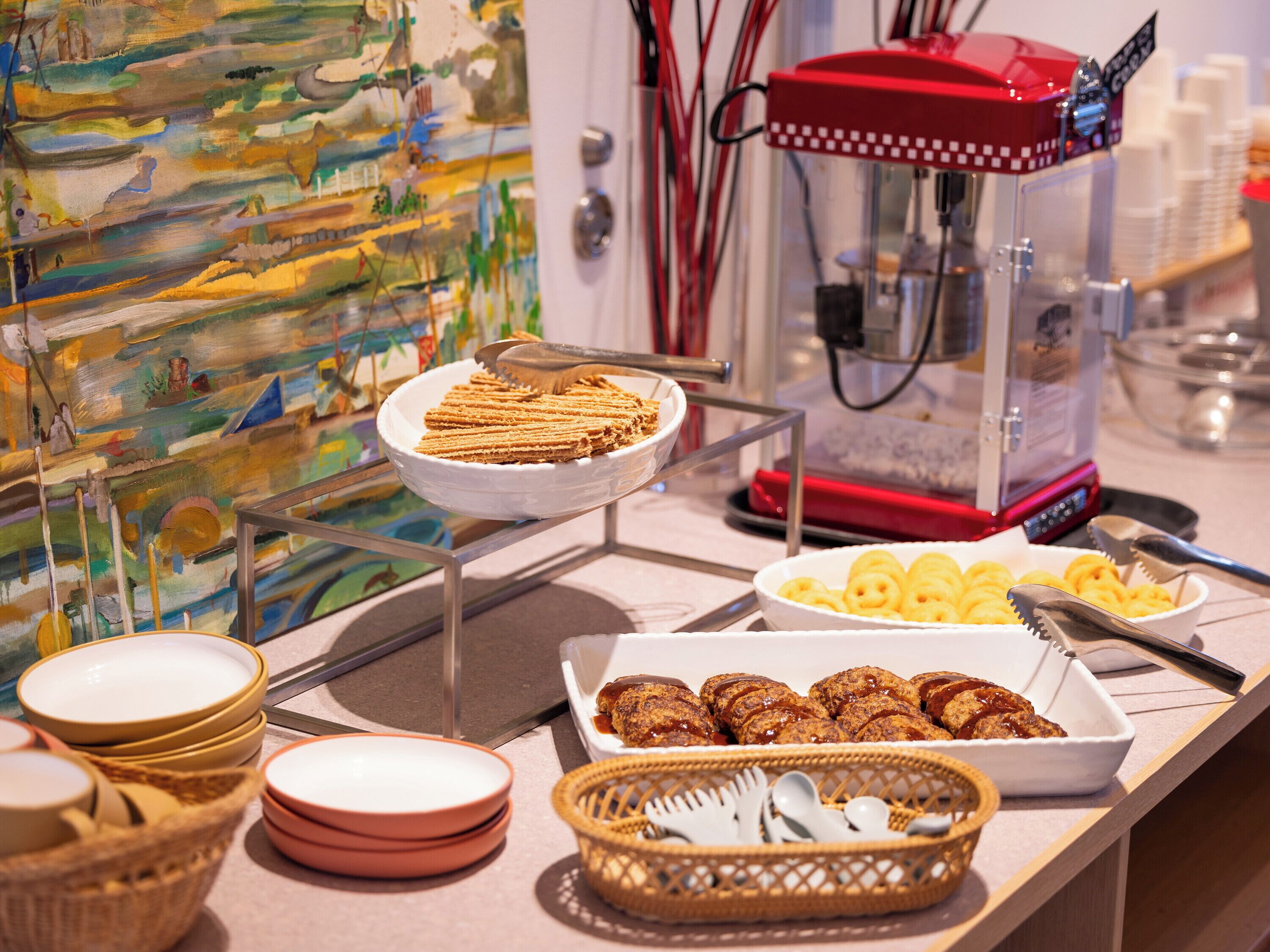 A buffet setup with various food items, including waffles, pastries, and a waffle iron.