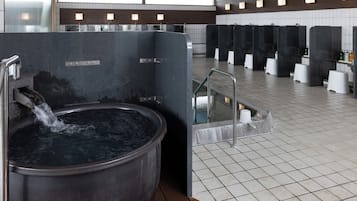 A modern bathroom with a large hot tub, multiple sinks, and a tiled floor.
