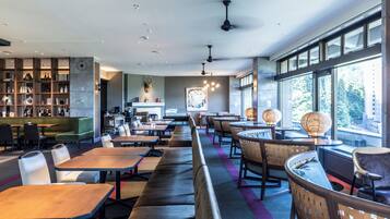 A modern restaurant with a long counter, booths, and a bookshelf.