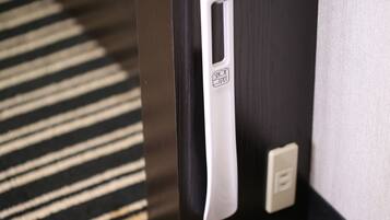 A door with a white handle and a shoe pedal, a power outlet, and a striped carpet.