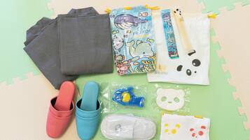A collection of children's items including shoes, a water bottle, a snack pouch, and a toy on a green mat.