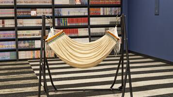A hammock in a room with a striped floor and a bookshelf in the background.