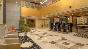 Un vestíbulo amplio con mostrador de recepción, zona de estar y una escalera que conduce a un nivel superior.