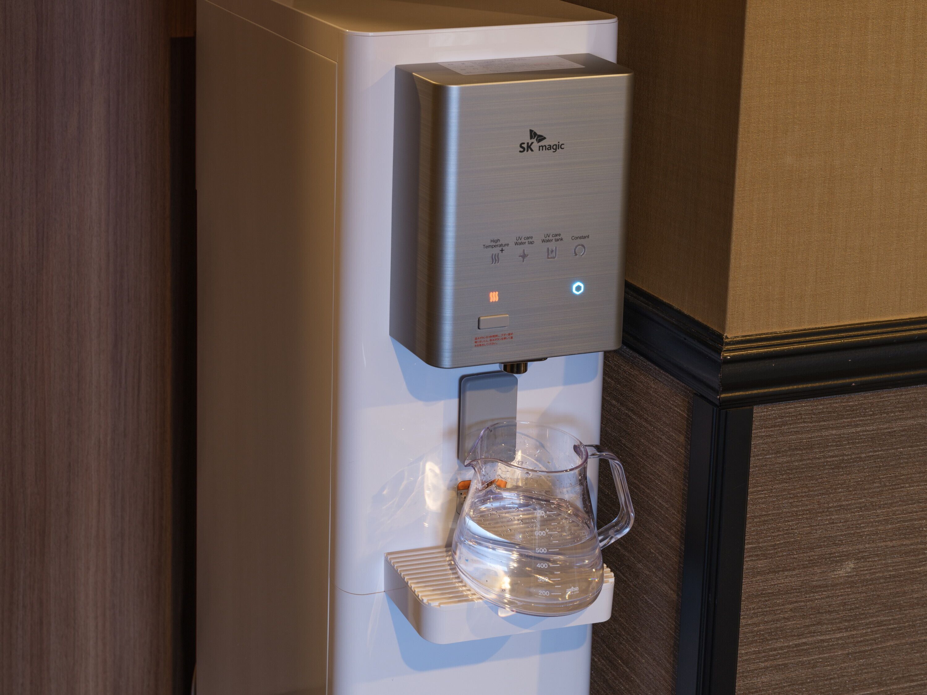Un dispensador de agua con una jarra transparente incorporada, que cuenta con un panel de control con varias opciones.