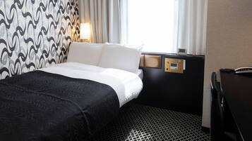 A hotel room with a bed, a desk, a control panel, and a window with curtains.