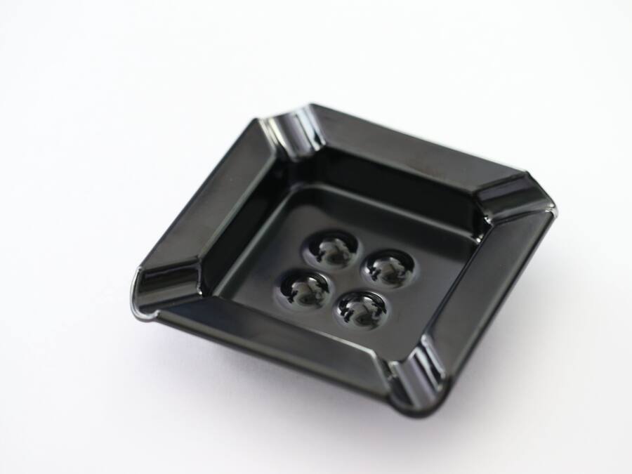 A black, square-shaped object with four circular indentations.