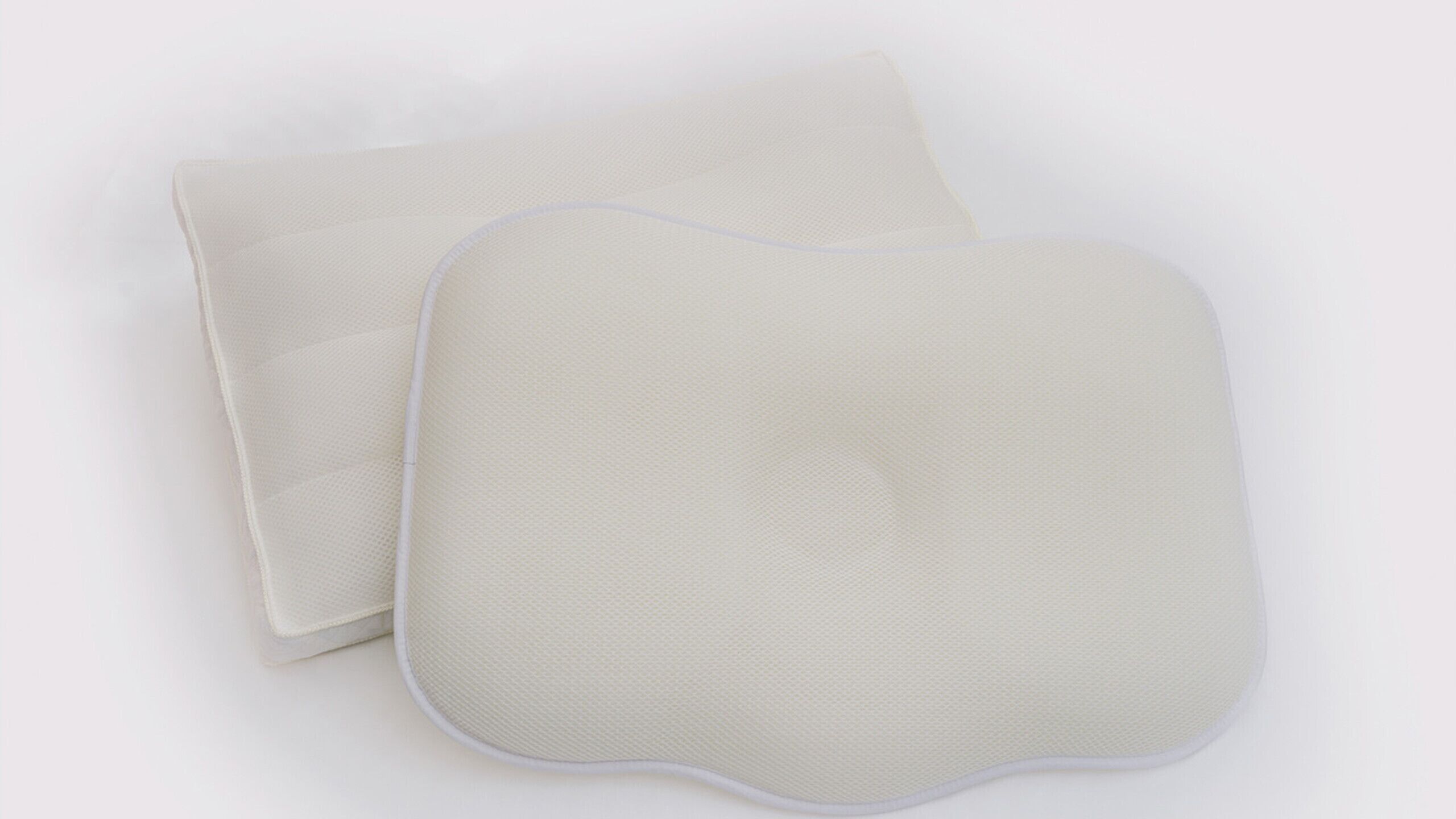 Two white, rectangular, padded objects with rounded edges, likely cushions or pads, on a plain background.