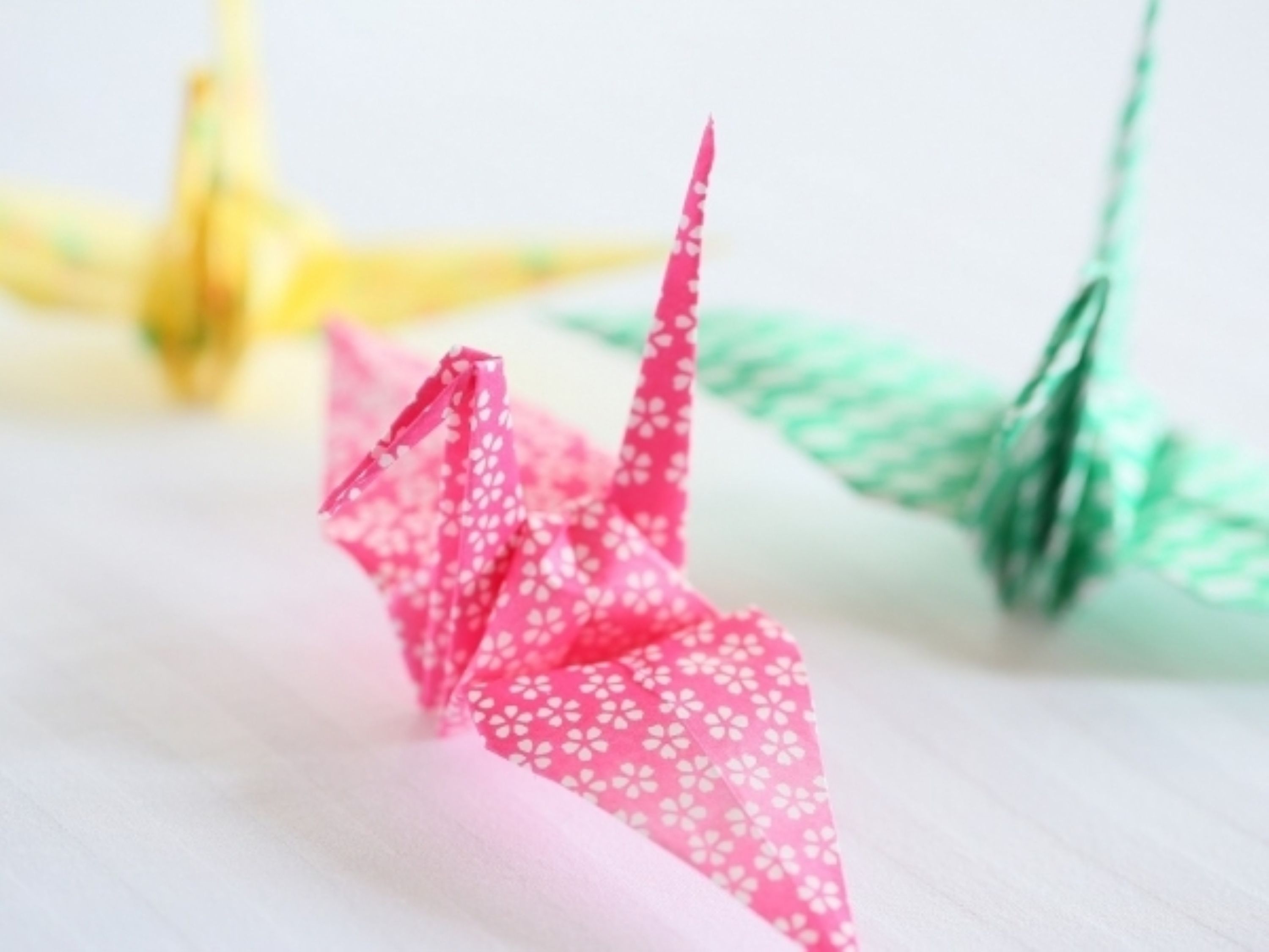 A close-up of origami cranes with pink and green colors.