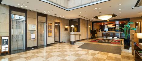 A spacious lobby with a checkered floor, a reception desk, and a chandelier.
