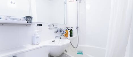 Un baño moderno con un lavabo blanco, un espejo, una ducha y un inodoro. Hay artículos de aseo en la encimera del lavabo.