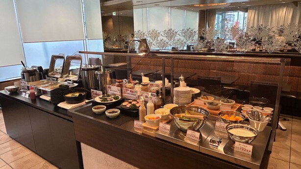 Een buffet met diverse gerechten en toevoegingen, waaronder sushi, salades en warme dranken.