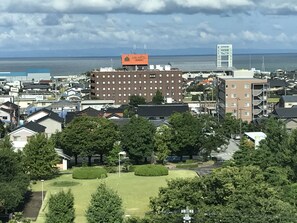 Un hotel con un edificio grande, un estacionamiento y vista al mar.