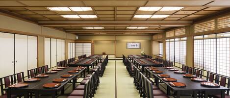 A conference room with long tables and chairs, a tatami mat floor, and large windows.