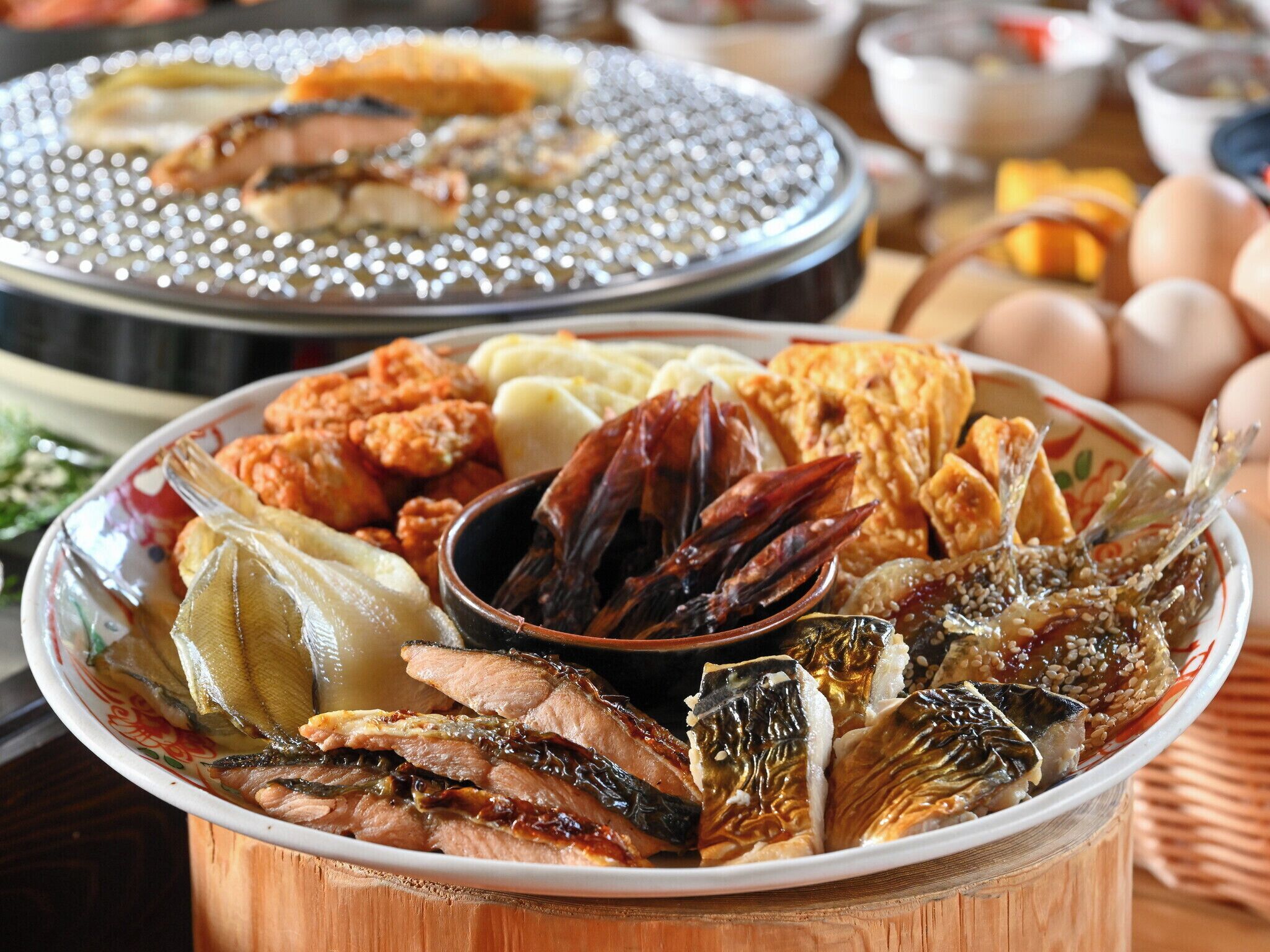 Un'ampia varietà di piatti, tra cui pesce, verdure e pane, su un tavolo di legno.