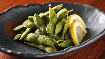 Una ciotola di fagiolini e mezza limone su un piatto scuro.