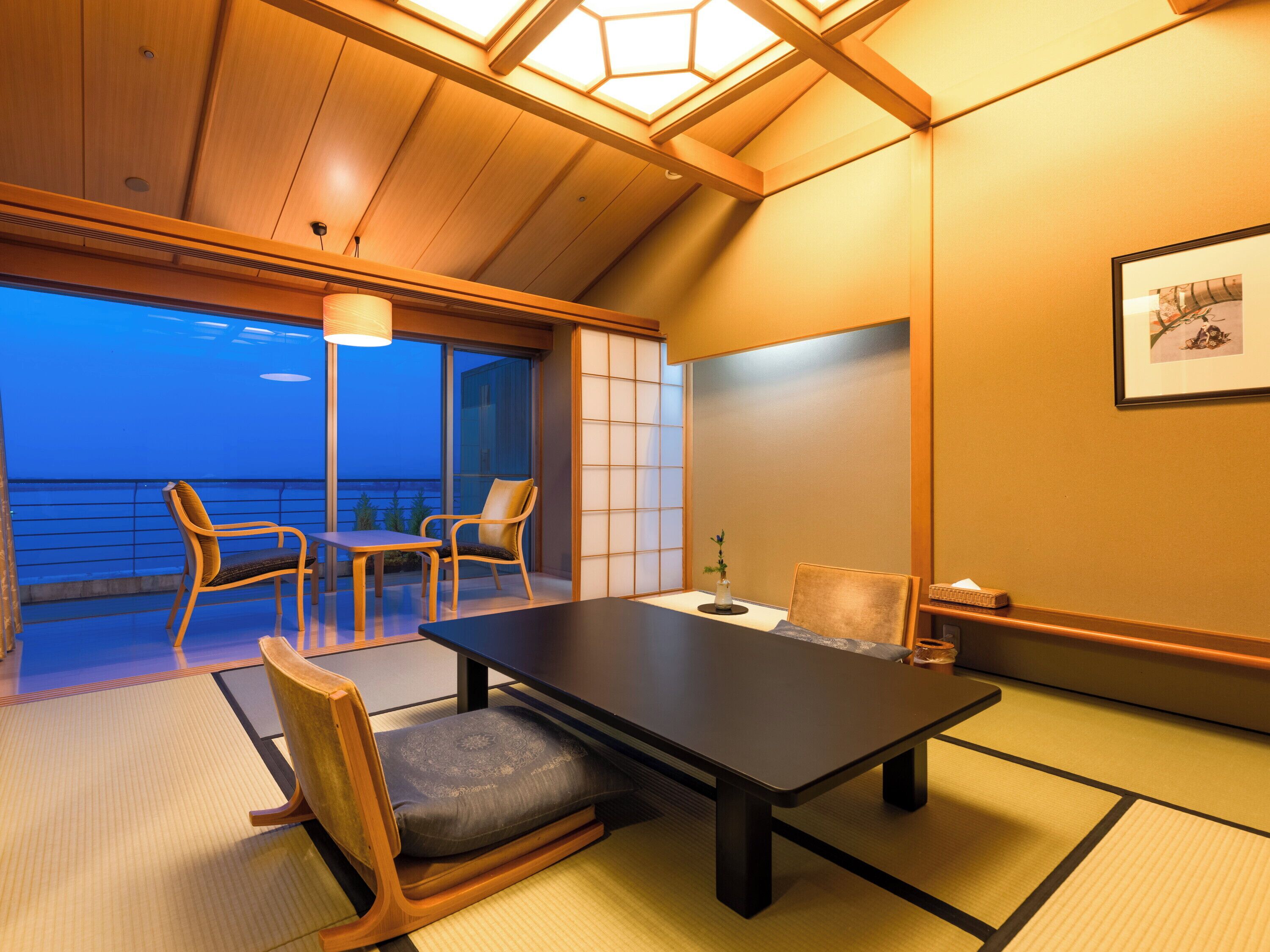 A traditional Japanese-style room with tatami flooring, a low table, and two chairs.