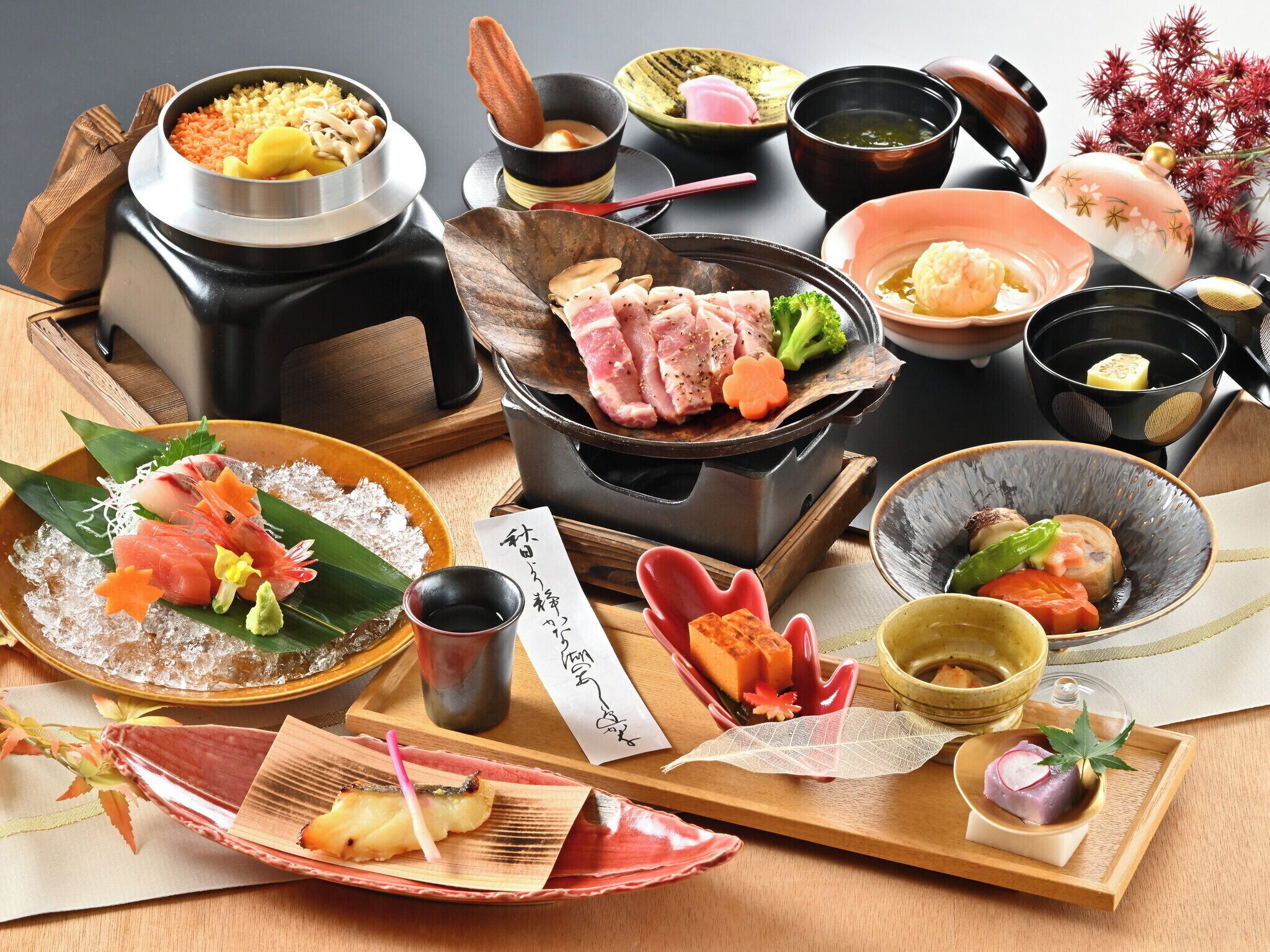 A variety of Japanese dishes including sushi, sashimi, and grilled meats, served on traditional ceramic and wooden plates.
