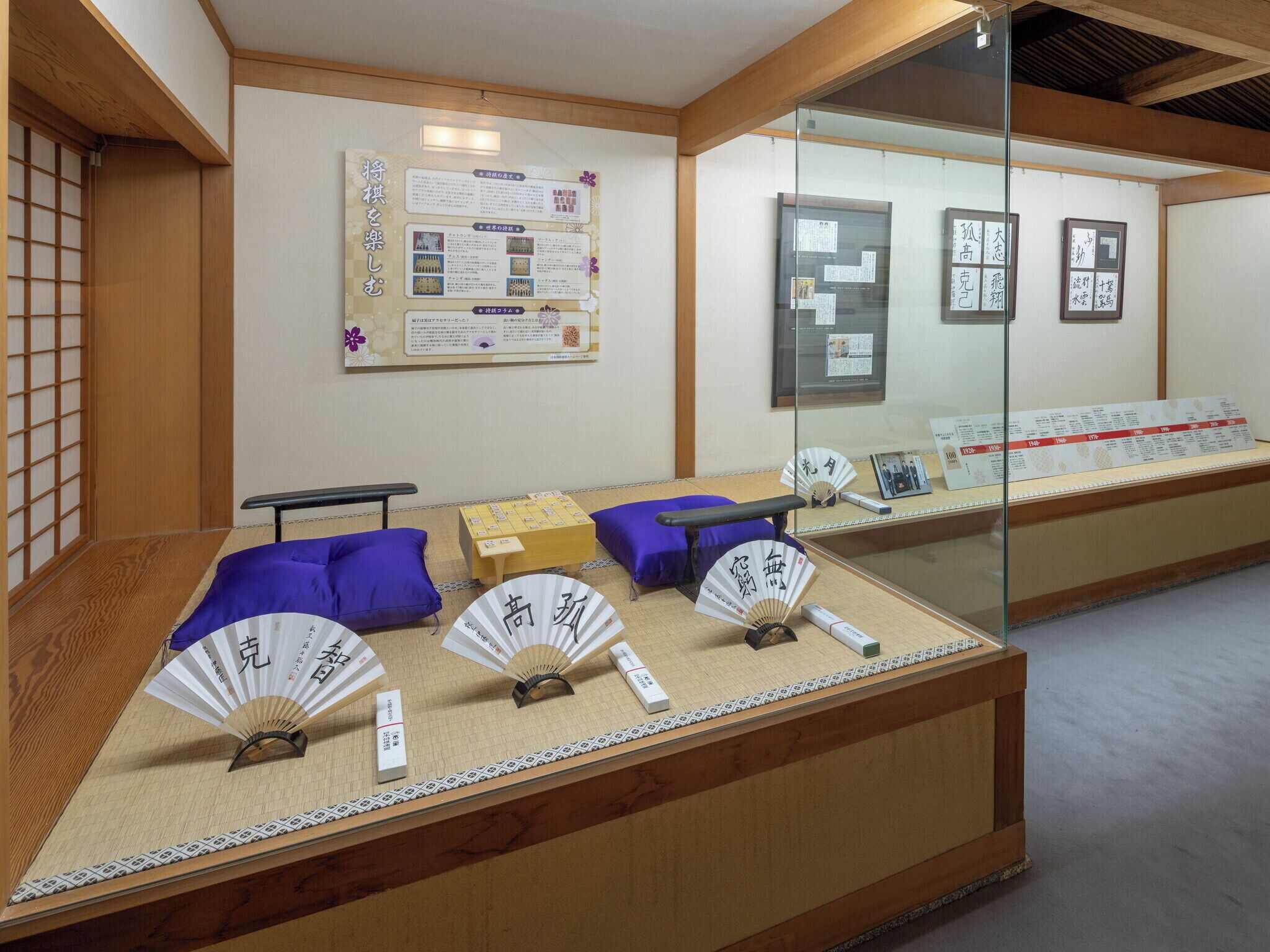 Una habitación tradicional japonesa con suelo de tatami, una mesa de madera baja y una exhibición de abanicos con caligrafía.
