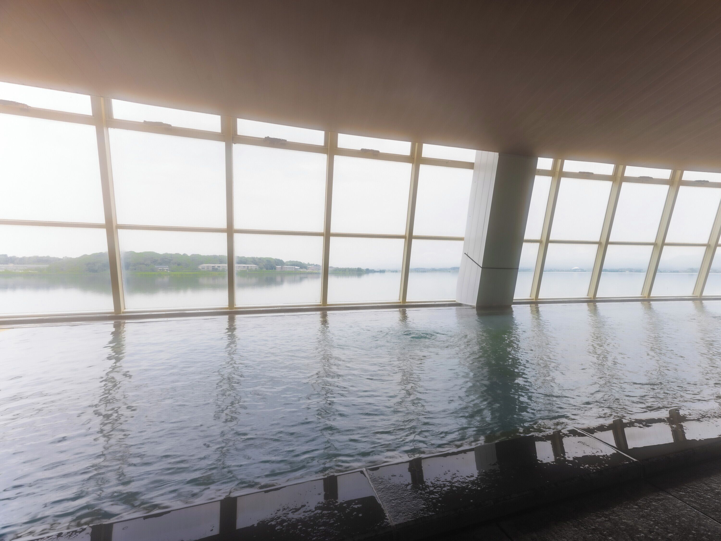 Una gran piscina interior con vistas a un lago a través de amplios ventanales.