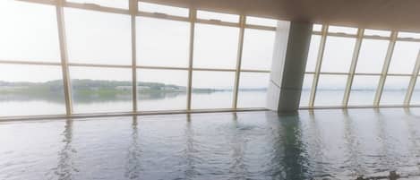 Una gran piscina interior con vistas a un lago a través de amplios ventanales.