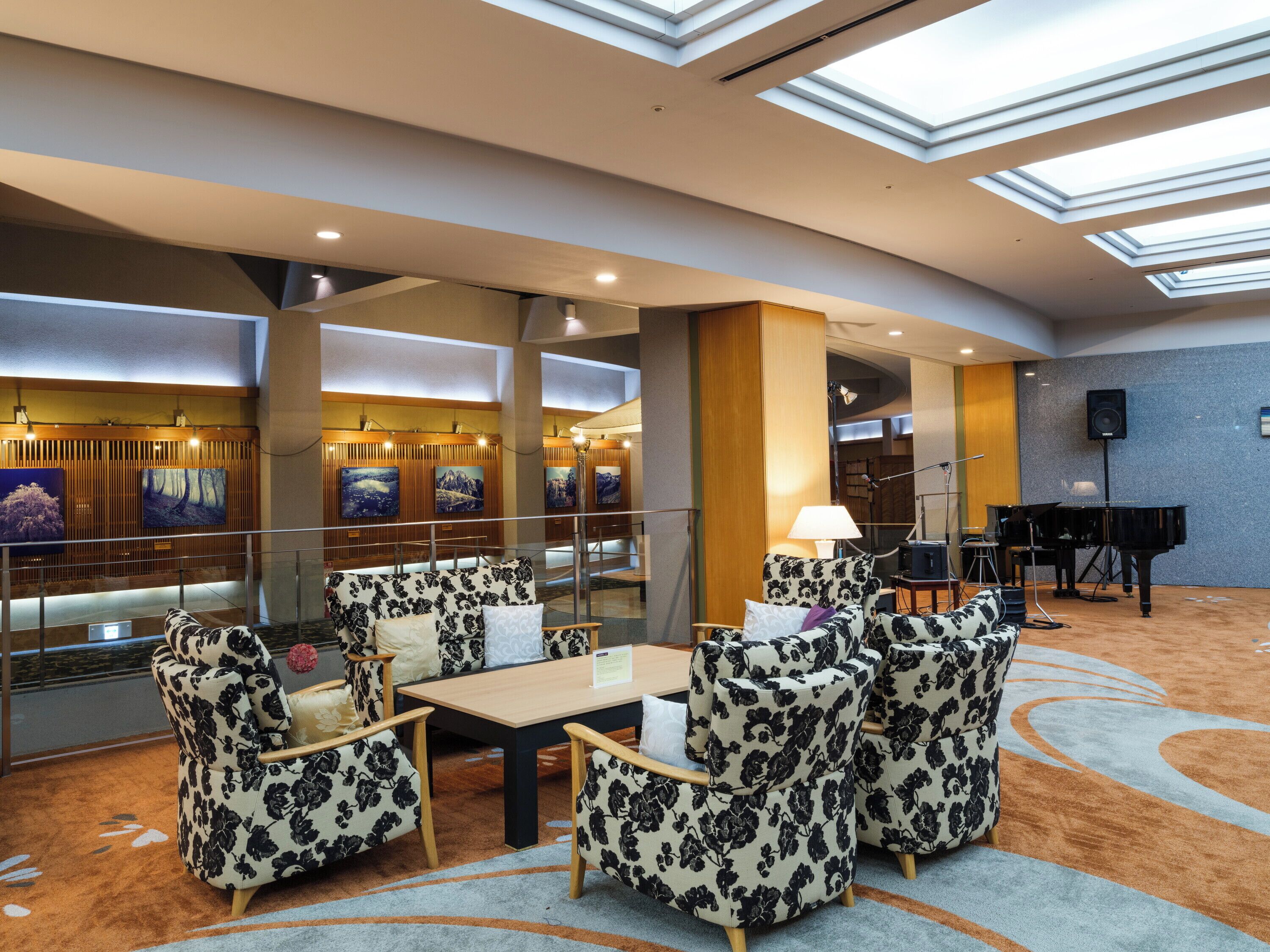 A lobby with a seating area, a piano, and artwork on the walls.