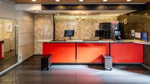 A reception area with a marble wall, a red counter, and a cash register.