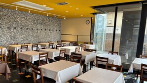 A restaurant with multiple tables and chairs, a patterned wall, and a clock on the wall.