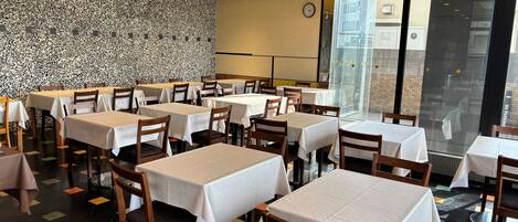 A restaurant with multiple tables and chairs, a patterned wall, and a clock on the wall.